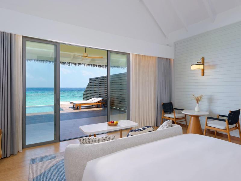 Chambre d'hôtel lumineuse avec vue sur une terrasse et la mer.