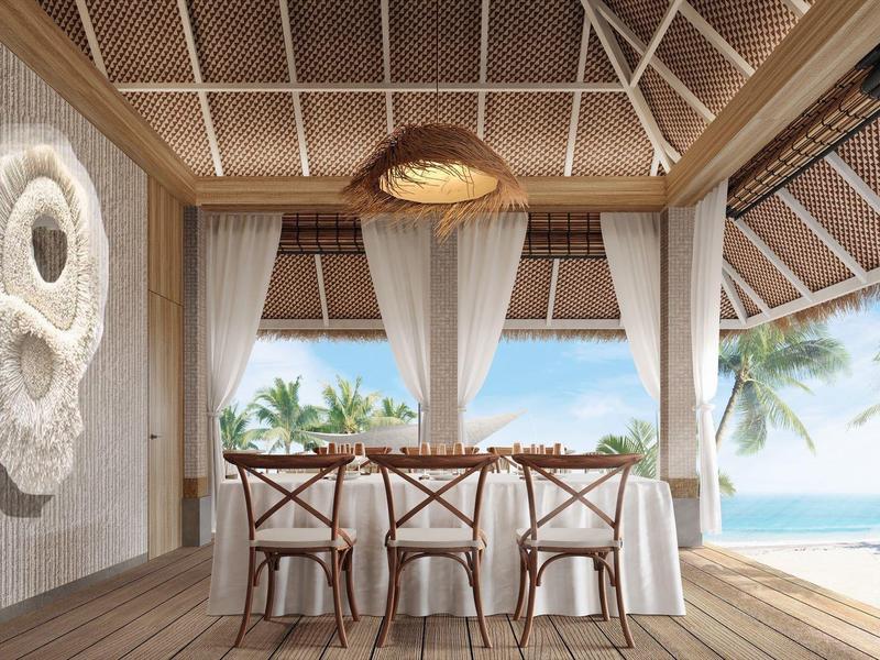 Coin repas avec tables et chaises en bois sur une terrasse ouverte avec vue sur la mer