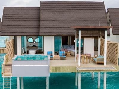 Bungalow mit Holzsteg und Terrasse über türkisem Wasser, ausgestattet mit Pool und Sitzbereich.