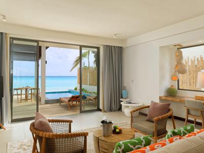 Modern eingerichtetes Wohnzimmer mit Blick auf das Meer durch große Glasfenster und Zugang zu einer Terrasse.