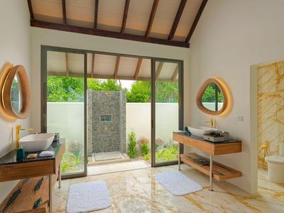 Heller Badezimmerbereich mit Außendusche, Holzrahmen und modernen Armaturen.