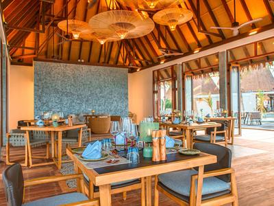 Modern eingerichtetes Restaurant mit Holztischen und Stühlen, Glasflaschen und Tafeln, natürliche Beleuchtung.