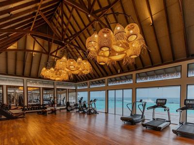 Geräumiger Fitnessraum mit Holzfußboden und Panoramafenstern mit Meerblick in einem Hotel.