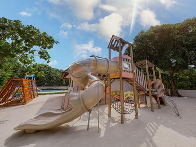 Großer Spielplatz mit Rutschen und Klettergerüsten in einem Hotelresort bei Sonnenschein.