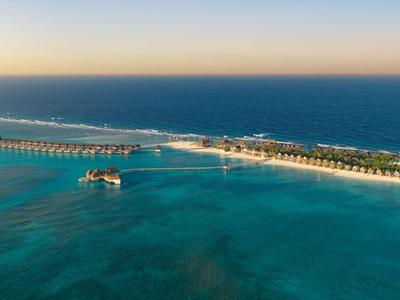 Luftaufnahme eines Resorts mit langen Stegen und klarem, blauem Wasser am Meer.