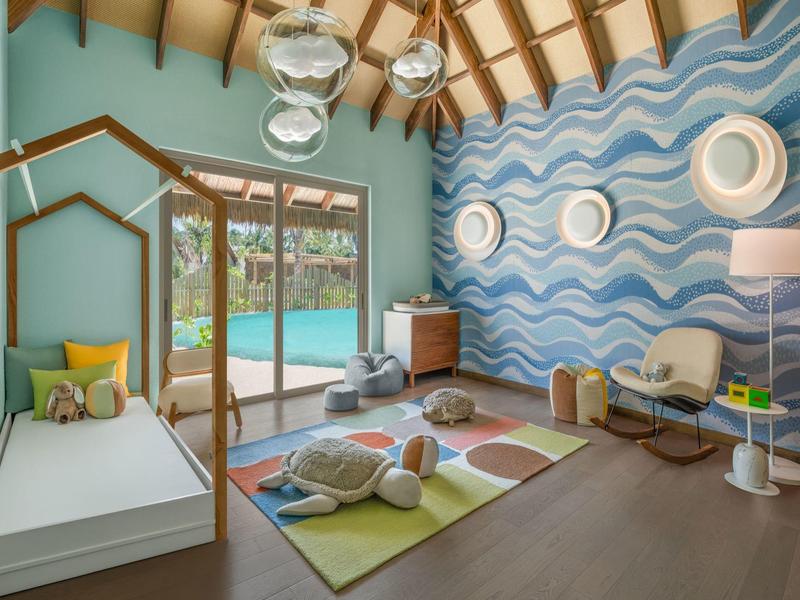 Camera per bambini con carta da parati a onde, letto singolo, tappeto gioco colorato e vista sulla piscina