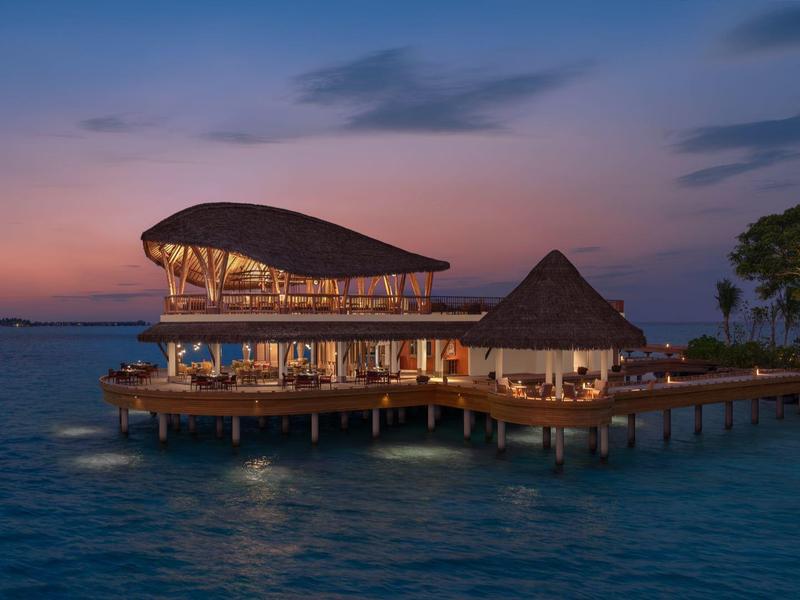 Un ristorante elegante su palafitte sull'acqua al tramonto.