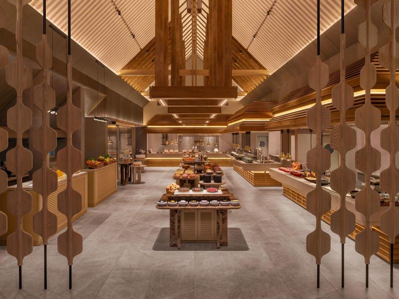 Elegante sala da pranzo dell'hotel con design in legno caldo e buffet al centro.