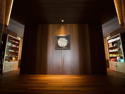 Dunkler Hotelraum mit Holzwänden, beleuchteten Regalen und dekorativer Uhr an der Wand.