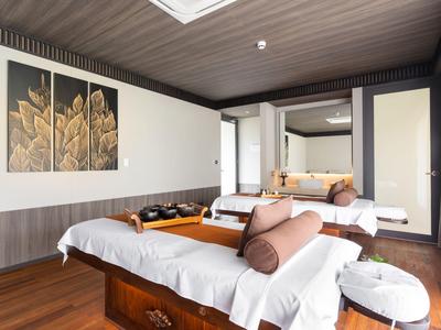 Modern eingerichteter Massageraum mit Holzboden, Behandlungsliege und warmen Farben.