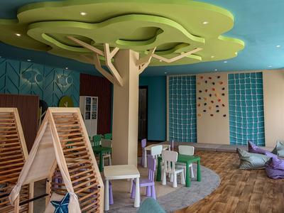 Kinderspielbereich mit kleinen Stühlen, Tischen und kletterbarer Wand in einem Innenraum