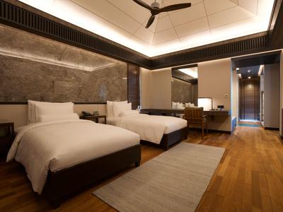 Modern eingerichtetes Hotelzimmer mit zwei Einzelbetten und Holzboden.