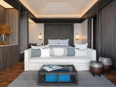 Modern eingerichtetes Wohnzimmer mit weißem Sofa, grauer Wand und dekorativen Elementen in einem Hotelzimmer.