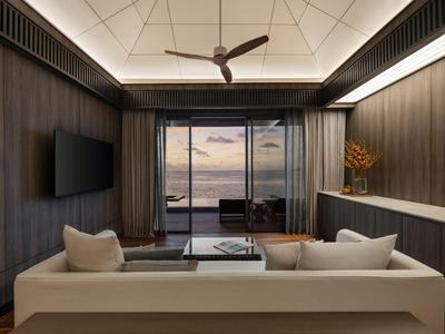 Modern eingerichtetes Hotelzimmer mit Sofa und Meerblick durch große Fenster.