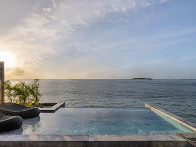 Infinity-Pool mit Liegestühlen und Blick auf das Meer bei Sonnenuntergang.