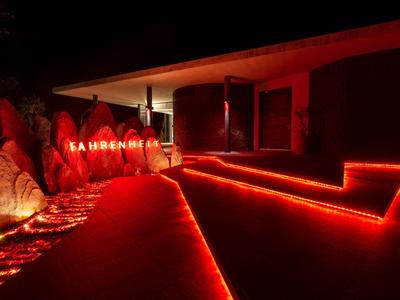 Rote Neonbeleuchtung betont Wege und Gebäude an einem Hotel oder Resort bei Nacht.