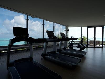 Moderne Fitnessgeräte in einem Raum mit großen Fenstern und Blick auf das Meer.