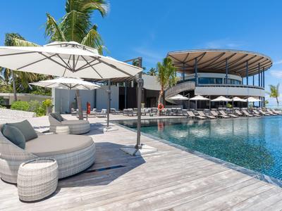 Moderner Poolbereich eines Hotels mit Holzdeck, Liegestühlen und großen Sonnenschirmen.