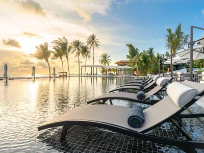 Luxuriöser Poolbereich mit Liegestühlen und Palmen bei Sonnenuntergang in einem Hotelresort.