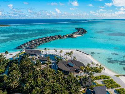 Tropisches Hotelresort mit Wasserbungalows und türkisblauem Meer unter blauem Himmel