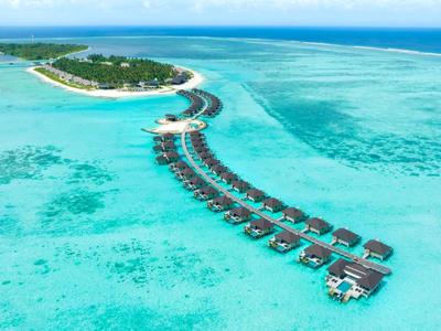 Überwasser-Bungalows führen zu einer tropischen Insel mit weißem Sandstrand und türkisfarbenem Wasser.