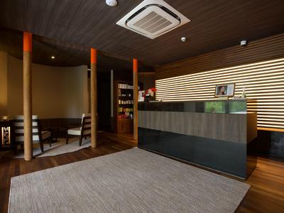 Moderne Hotellobby mit dunklen Holzmöbeln, Rezeptionstresen und gemütlichem Sitzbereich.