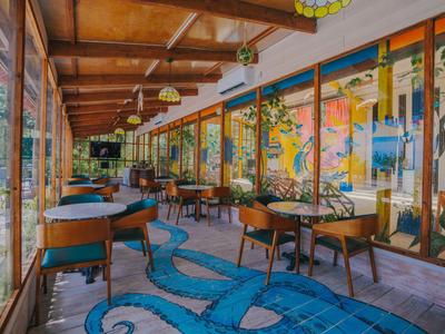 A colorful hotel dining area with wooden furniture and a blue octopus carpet.
