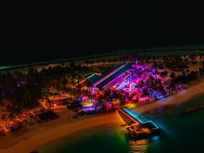 Island resort with colorful lights and piers in dark night sea.