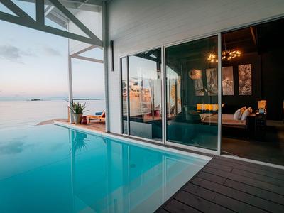 Infinity pool overlooking the ocean from a modern hotel room with glass facade.