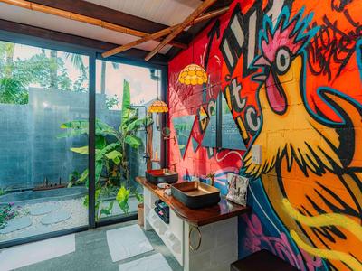 Colorful rooster mural in a bright room with glass sliding door and plants outside.