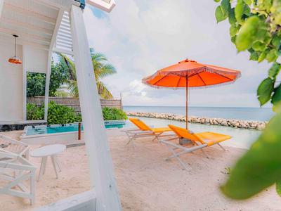 Beach view with orange loungers and umbrella, sand and sea in the background.