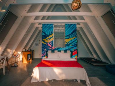 Modernly furnished bedroom with loft and artistic wall decoration in a cozy hotel.