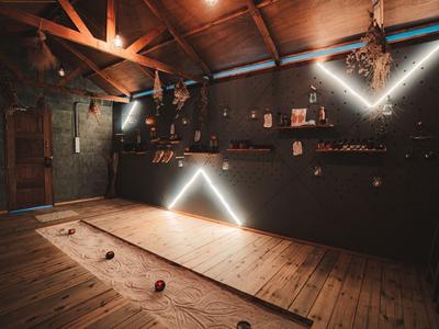 Rustic interior with wooden floor, dark walls, and modern LED lighting shaped like arrows.