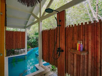 Outdoor shower and pool area with wooden fences and green surroundings.