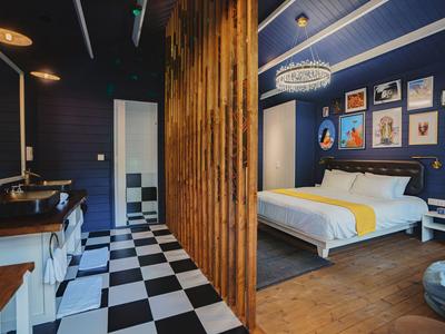 Modern hotel room with wood accents, dark blue walls, and checkerboard pattern in the bathroom