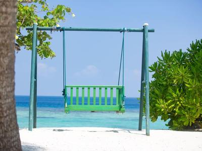Green swing on white sandy beach overlooking calm turquoise sea