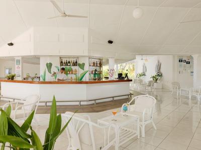 Bright, modern hotel bar with white furniture and plants for a relaxed atmosphere.
