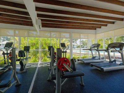 A modern gym with treadmills, bikes, and strength equipment by large windows.