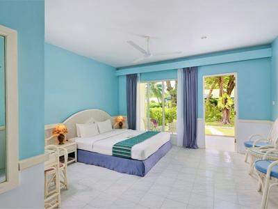 Světle modrý hotelový pokoj s modro-bílým zařízením a výhledem na tropickou zahradu.