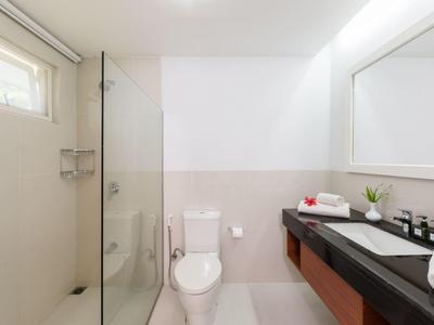 Moderní koupelna se sprchou, toaletou, velkým zrcadlem a černou pracovní deskou.