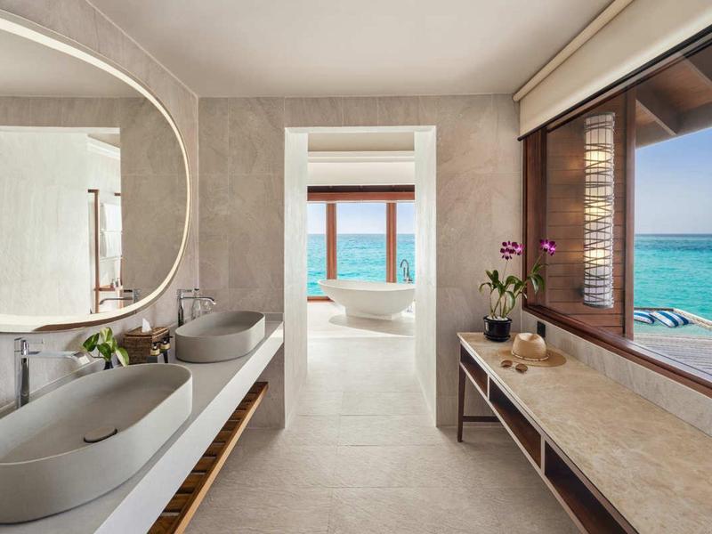 Světelná koupelna se dvěma umyvadly a výhledem na moře přes velké okno.