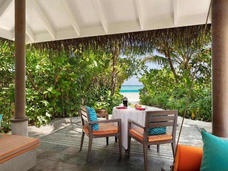 Pohodlný venkovní prostor s prostřeným stolem a výhledem na tropickou zahradu a moře