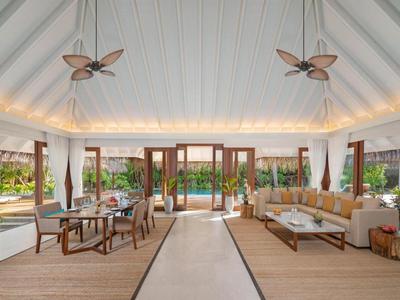 Großer, heller Wohnraum mit Holzboden, hohen weißen Decken, Ventilatoren und Glasfront zum Garten.