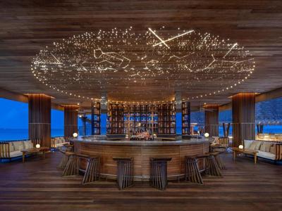 Runder Barbereich mit Holzdesign und Sternenlichtdecke in moderner Hotelbar bei Nacht.