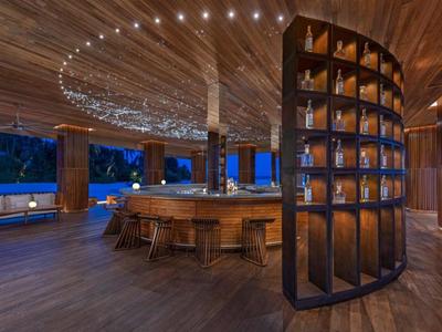 Moderner Hotelbarbereich mit geschwungenem Holzdesign und stimmungsvoller Beleuchtung