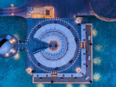 Luftaufnahme eines modernen schwimmenden Gebäudes mit kreisförmigem Design auf Wasser bei Nacht.