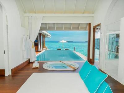 Terraza luminosa del hotel con piscina, jacuzzi y vista al mar azul bajo un clima soleado.