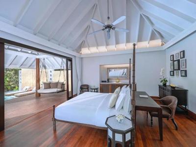 Dormitorio luminoso con suelo de madera, cama grande y balcón contiguo con zona de descanso.