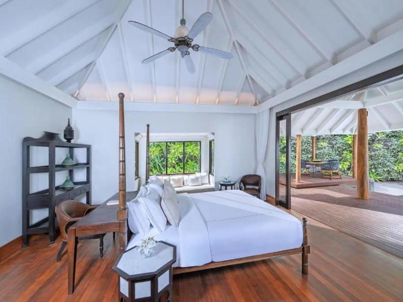 Dormitorio luminoso con cama dosel, suelo de madera y acceso a terraza con vista a la vegetación.