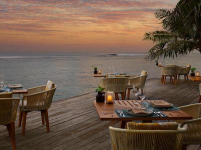 Taras z stołami i krzesłami nad morzem podczas zachodu słońca.